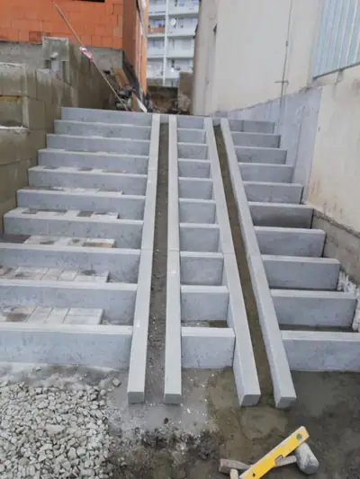 Betonové schodiště mezi zdmi s kolejnicemi pro kočárek