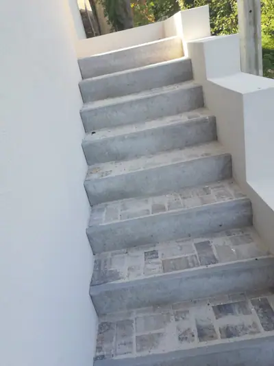Úzké schodiště mezi bílými zdmi, stupně z betonu a dlažby
