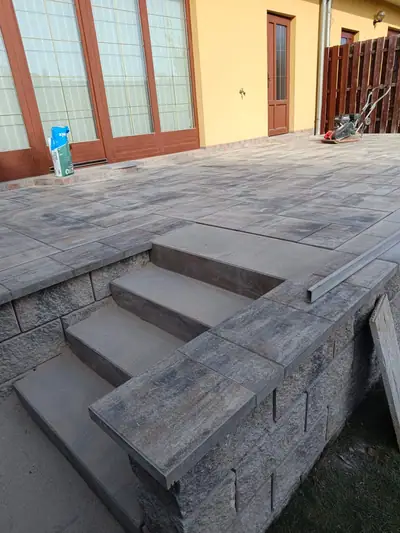 Terasa ze šedé dlažby se schody a zídkou ze štípaných tvárnic