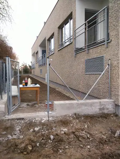 Sloupky plotu se vzpěrami a branka u bytového domu