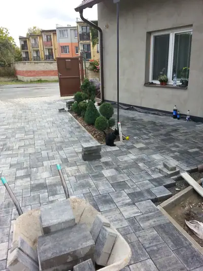 Dlážděný dvůr v šedém melíru před domem
