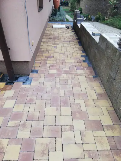 Chodník z dlažby v okrovém a cihlovém melíru podél domu